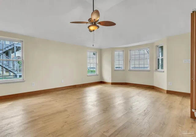 a view of an empty room with a window and wooden floor