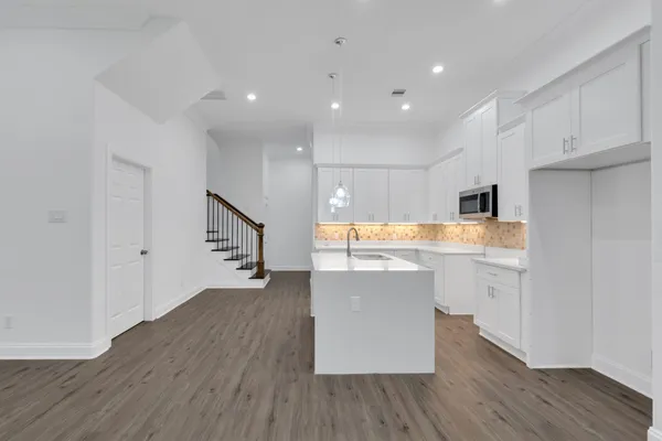 a room with stainless steel appliances kitchen island wooden floors and white walls