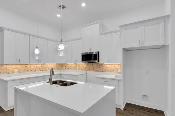 a kitchen with stainless steel appliances a sink a microwave a stove and white cabinets