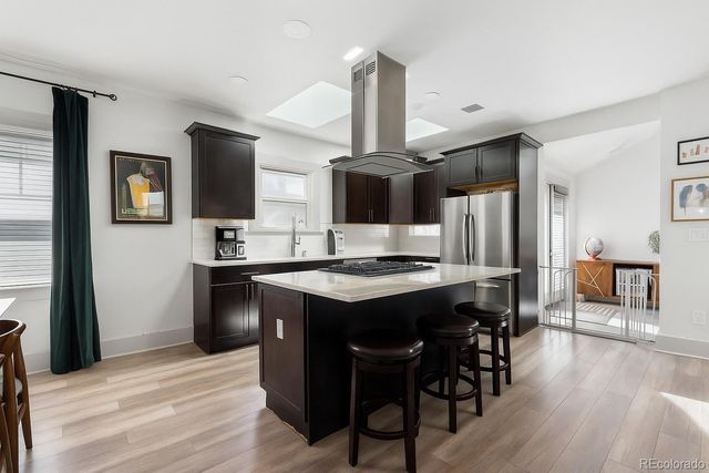 a kitchen with stainless steel appliances kitchen island granite countertop a table chairs microwave and sink