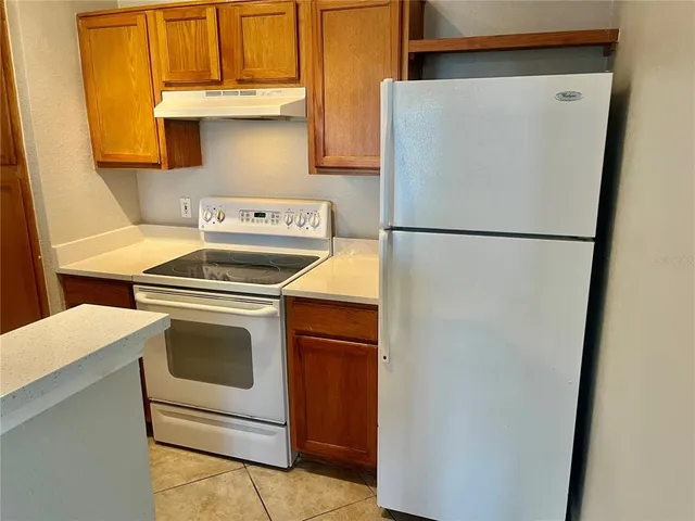 a white refrigerator freezer and a stove sitting inside of a kitchen