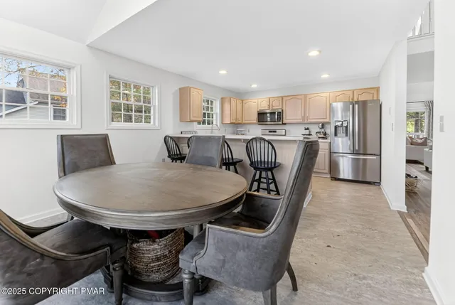 a living room with stainless steel appliances furniture a dining table and kitchen view