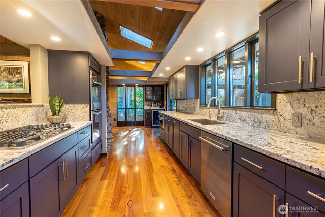 a large kitchen with stainless steel appliances granite countertop plenty wooden cabinets counter space a sink and a large window