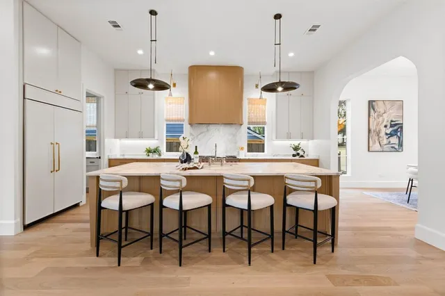 a dining room with stainless steel appliances kitchen island granite countertop a table chairs and a refrigerator