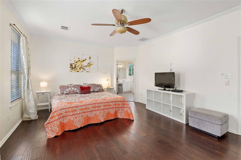 2730 Kinney Oaks Court Austin, TX 78704 - Photo 14 of 32 Spacious, light-filled primary suite featuring rich hardwood floors and elegant crown molding, creating a warm and inviting retreat.