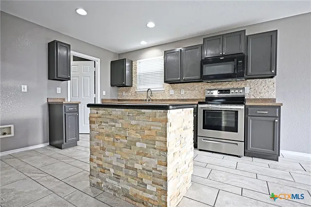 a kitchen with stainless steel appliances granite countertop a stove microwave and sink