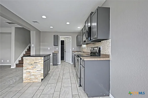 a kitchen with stainless steel appliances granite countertop a stove a sink and a refrigerator