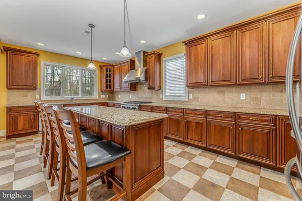a kitchen with stainless steel appliances granite countertop wooden cabinets a dining table and chairs