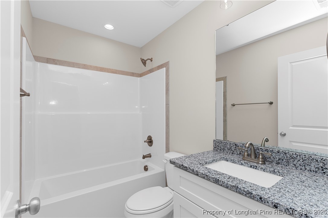 162 Surles Landing Way Benson, NC 27504 - Photo 13 of 28 a bathroom with a granite countertop sink toilet mirror and bathtub