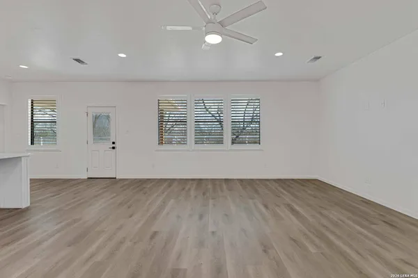 an empty room with wooden floor and windows