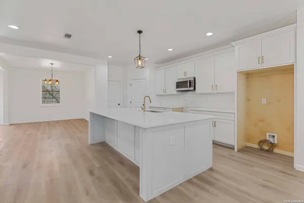 a large white kitchen with a sink a window and stainless steel appliances