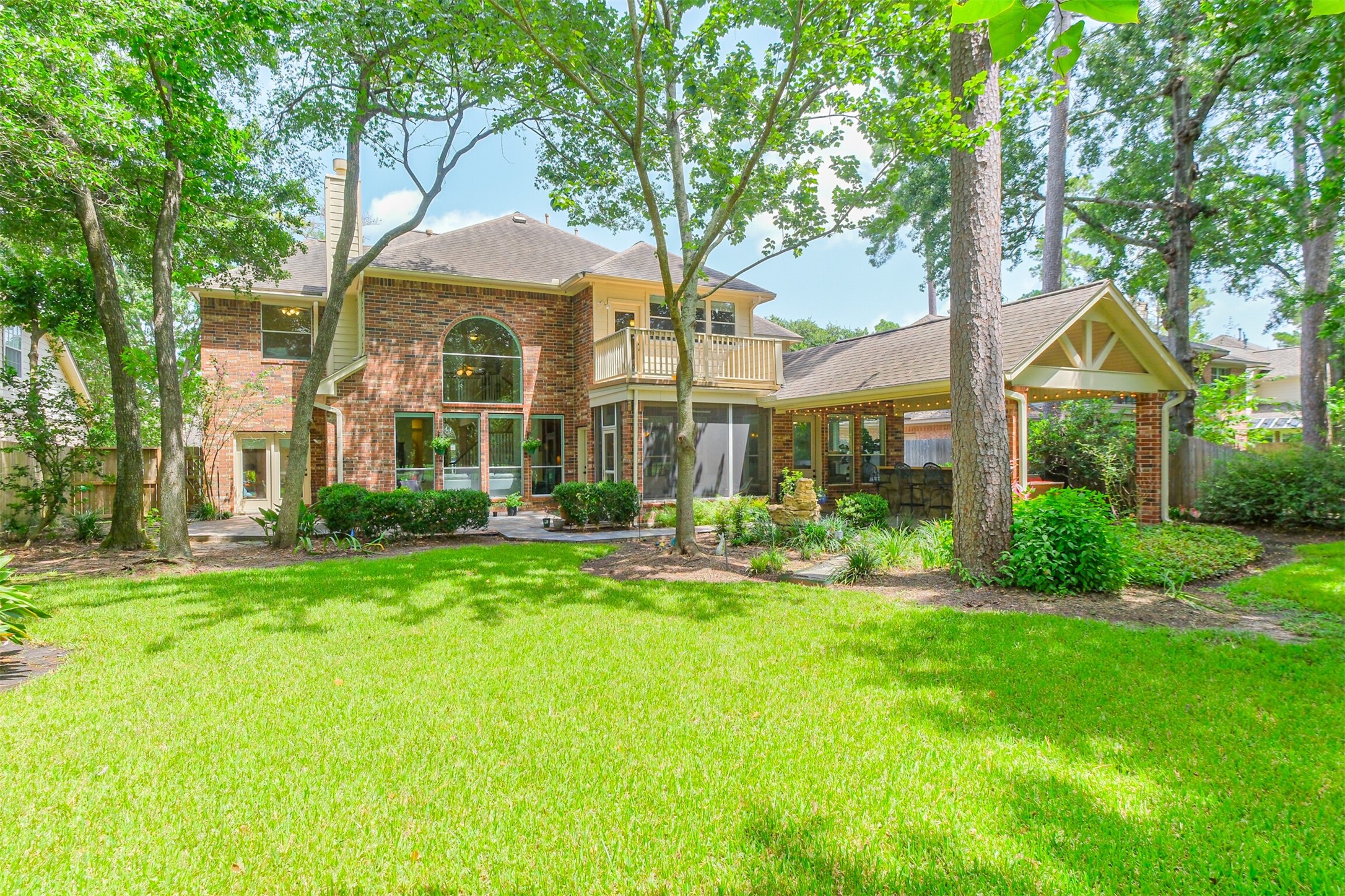 14919 Codys Run Cypress, TX 77429 - Photo 2 of 32 The beautifully landscaped backyard offers multiple spaces to gather and unwind, including a screened patio, covered outdoor kitchen, and a private second-story balcony overlooking the lush grounds. Towering trees provide shade and privacy. With plenty of green space for children, pets, or future pool plans, this backyard is as functional as it is beautiful.