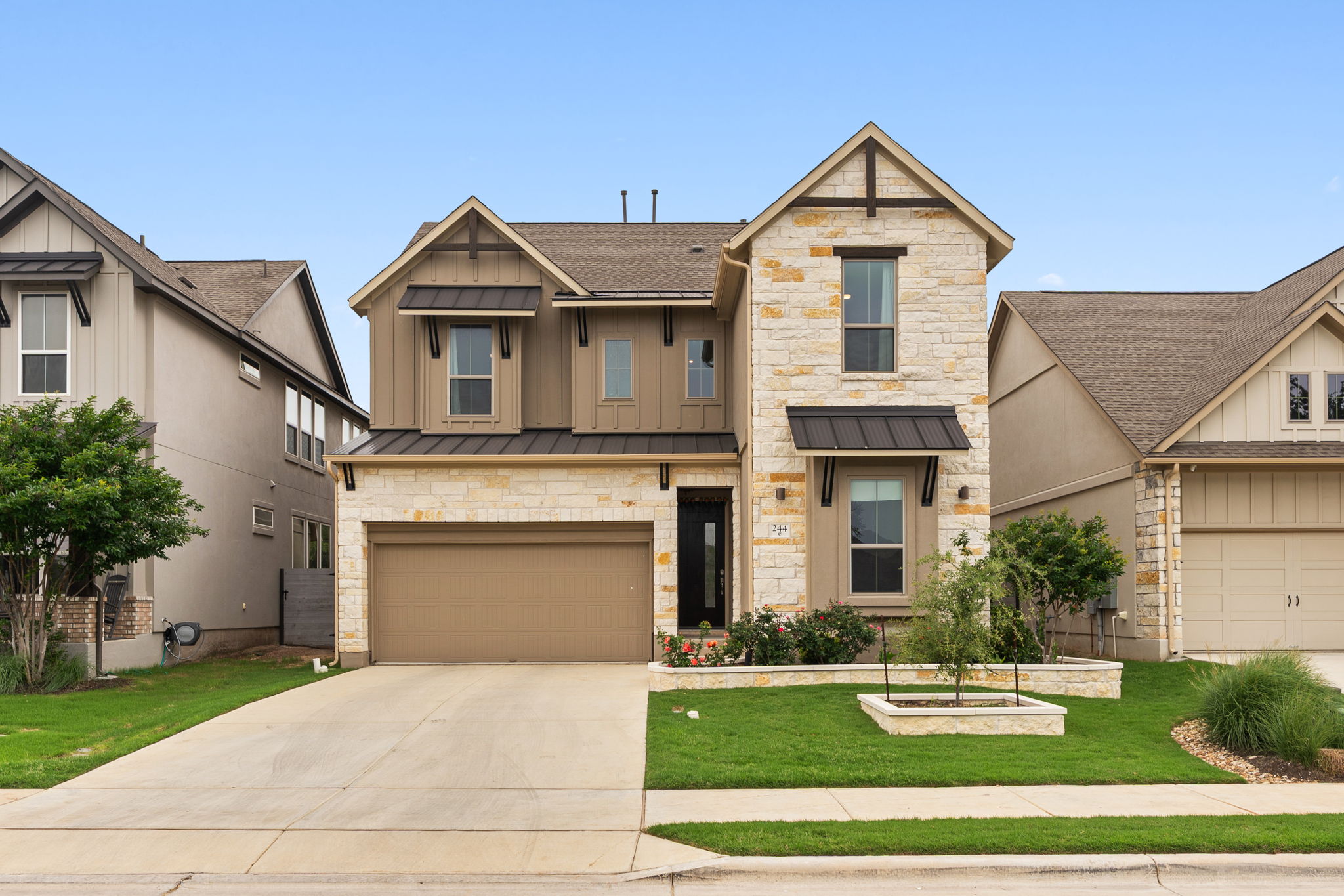 Two-story residence featuring a stone and board-and-batten facade with dark trim accents.