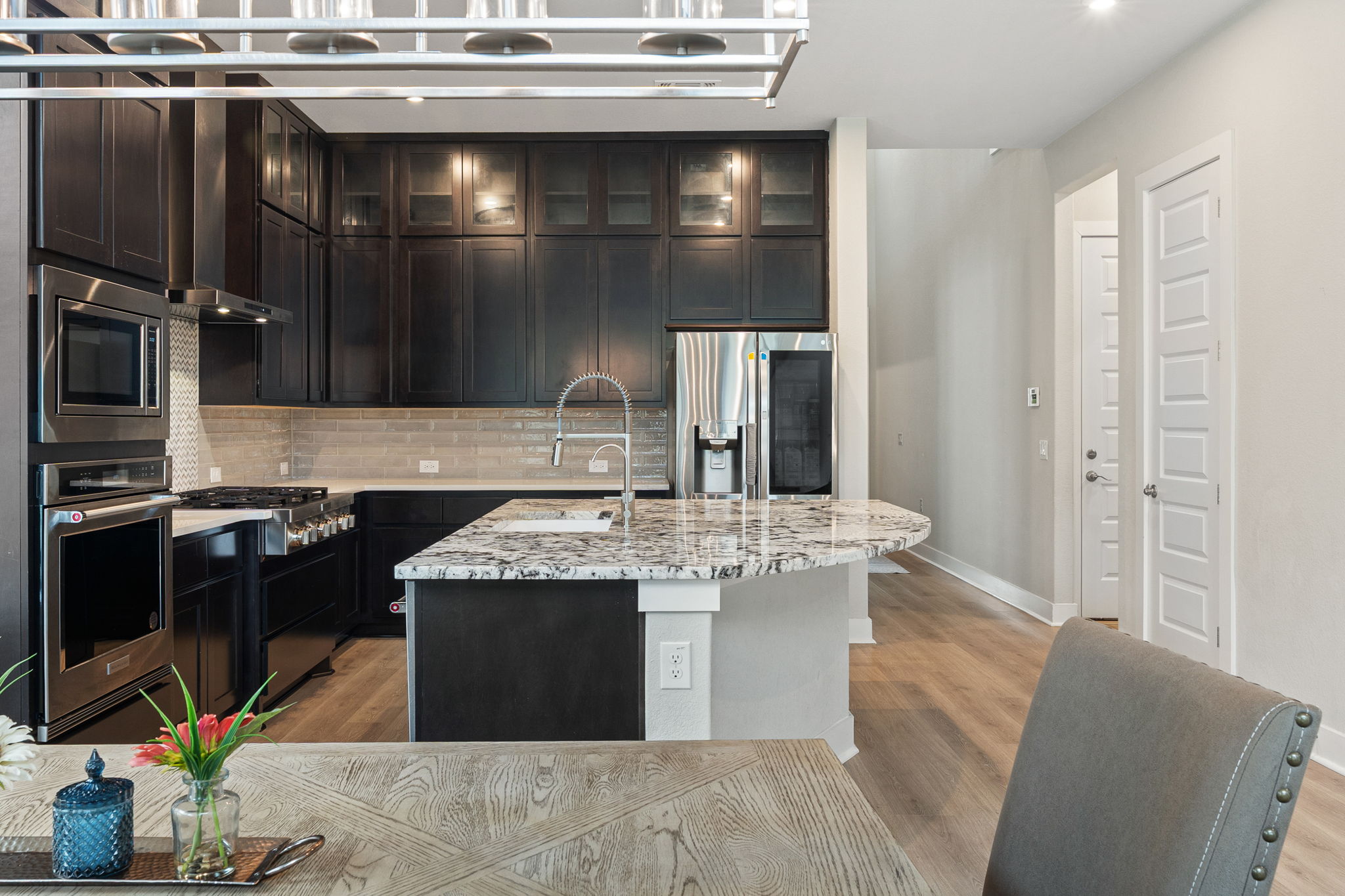 244 Diamondback Drive Georgetown, TX 78628 - Photo 11 of 37 Gourmet kitchen with dark cabinetry, stainless steel appliances, a subway tile backsplash, and a large island.