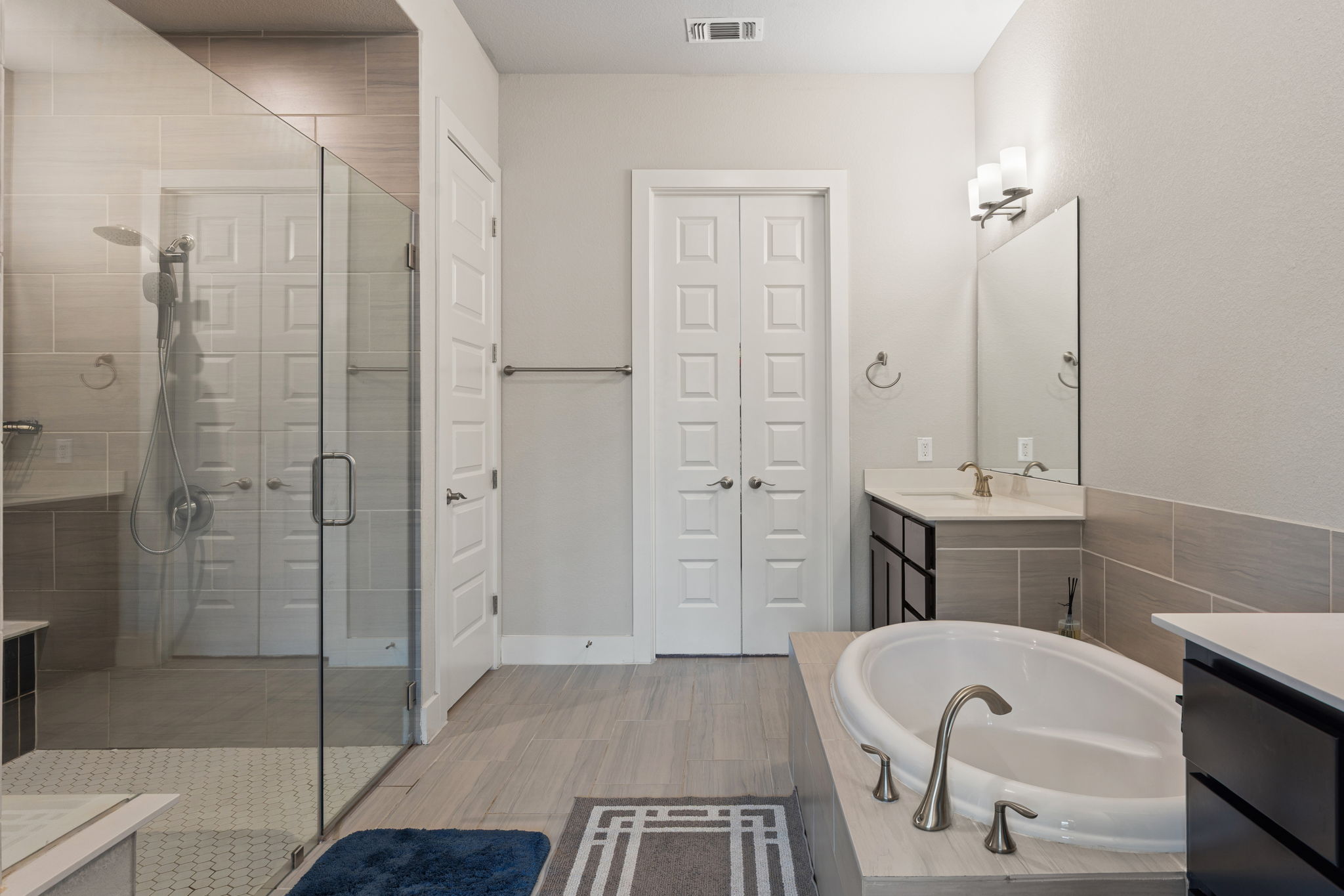 244 Diamondback Drive Georgetown, TX 78628 - Photo 20 of 37 Bathroom featuring a freestanding soaking tub, enclosed shower with a built-in bench, double vanity, wood-finish flooring, and light-colored wall tiling