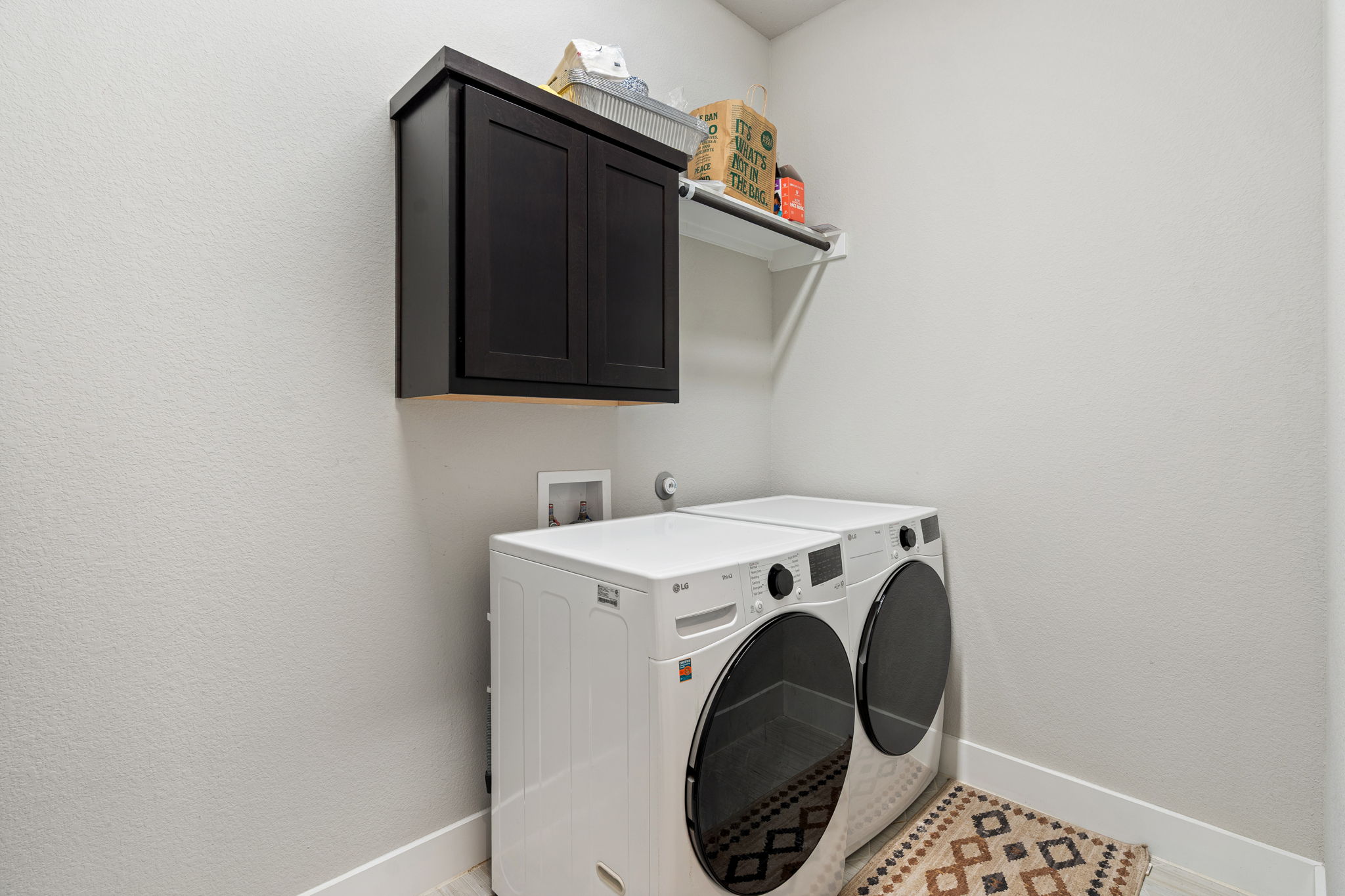 244 Diamondback Drive Georgetown, TX 78628 - Photo 26 of 37 Dedicated laundry area featuring a wall-mounted dark cabinetry, an open white shelving unit, and light gray wall paint.