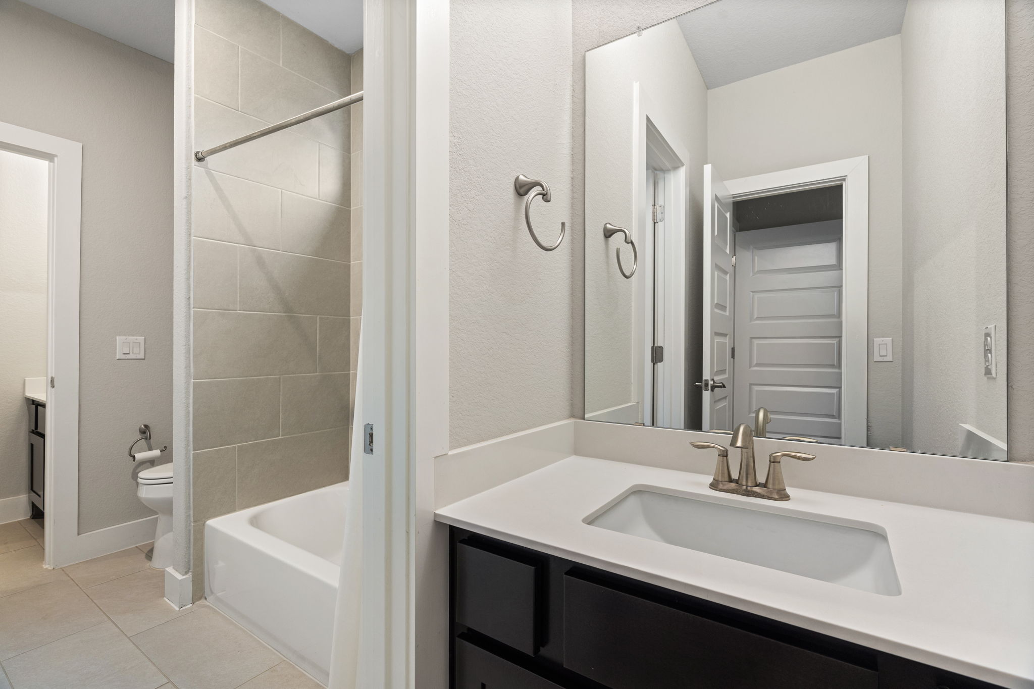 244 Diamondback Drive Georgetown, TX 78628 - Photo 31 of 37 Bathroom featuring a dark wood vanity with a white countertop, undermount sink, and brushed nickel faucet.