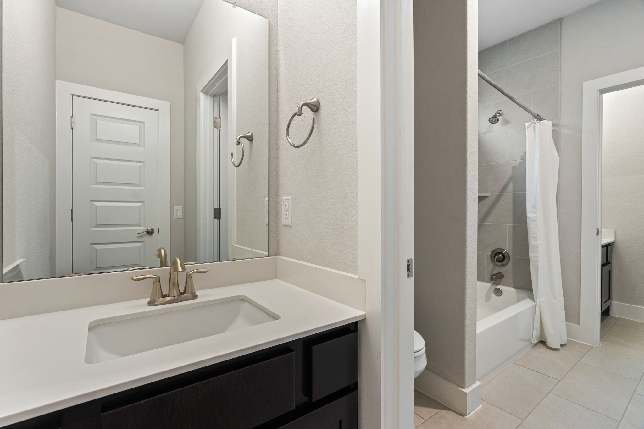 244 Diamondback Drive Georgetown, TX 78628 - Photo 32 of 37 Bathroom featuring a dark wood-finish vanity with a white countertop and integrated sink, brushed nickel faucet, and a large wall-mounted mirror.