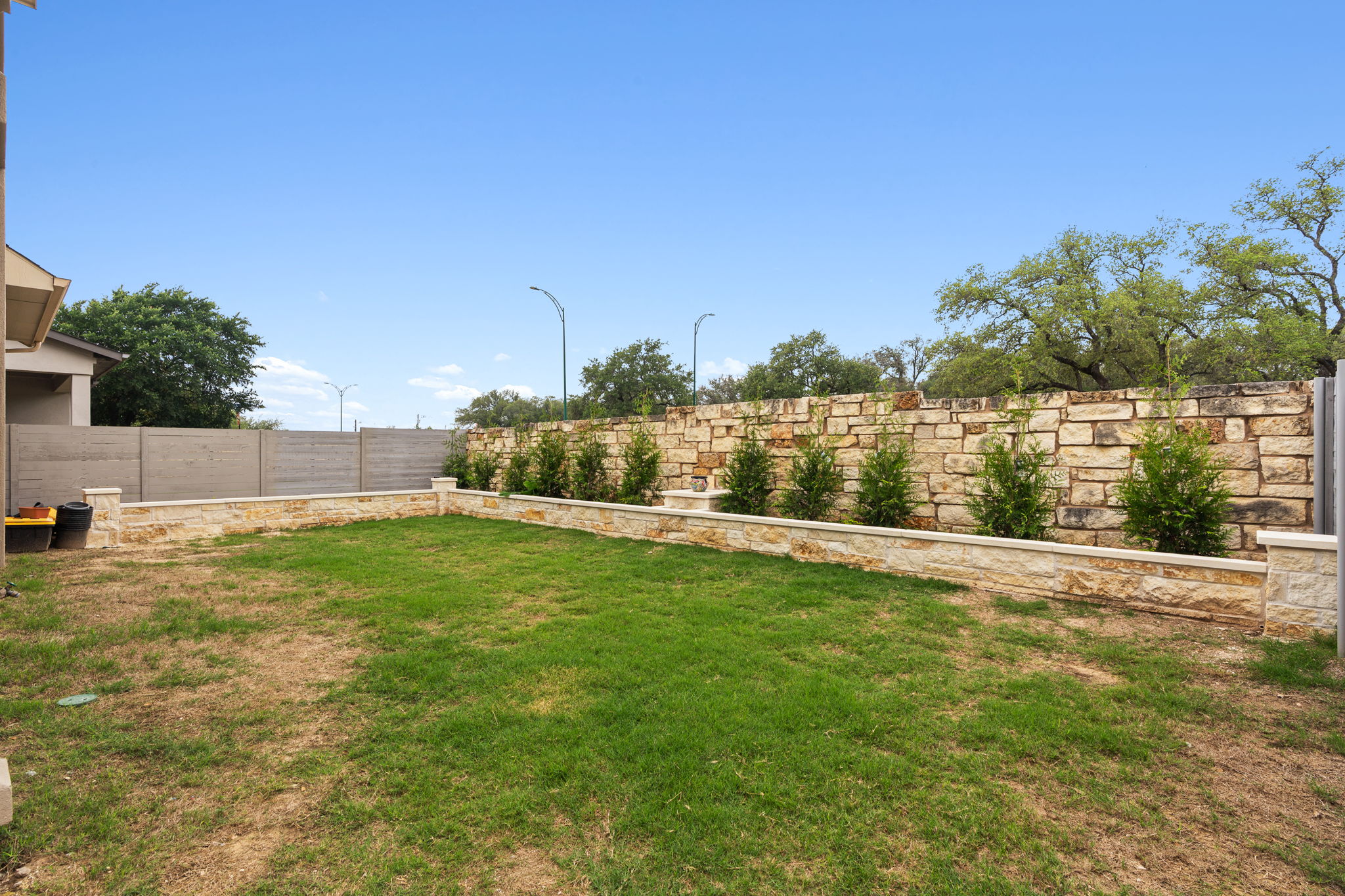 244 Diamondback Drive Georgetown, TX 78628 - Photo 33 of 37 Manicured lawn area featuring a stone retaining wall with integrated plantings.