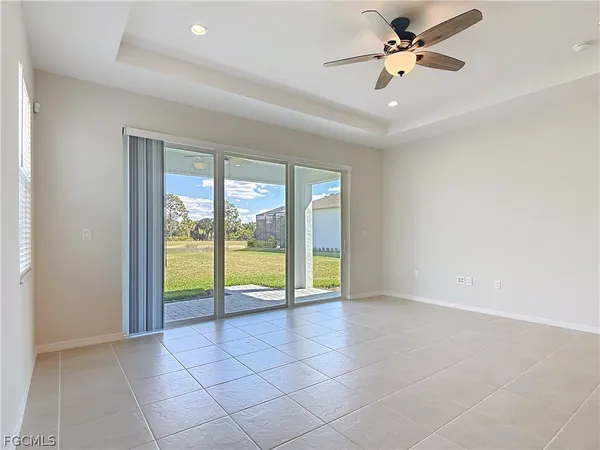 an empty room with floor to ceiling windows and a ceiling fan