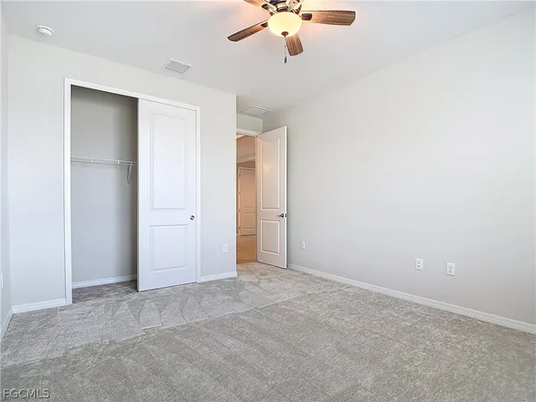 an empty room with a ceiling fan and carpet