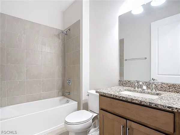a bathroom with a granite countertop sink a toilet and shower