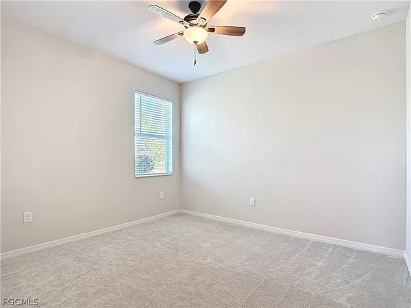 an empty room with a window and a fan