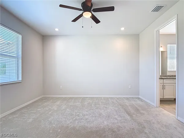 an empty room with windows and fan