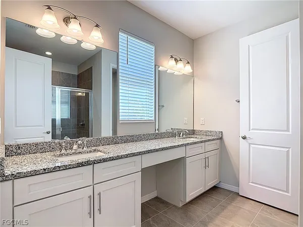 a bathroom with a granite countertop double vanity sink and a mirror