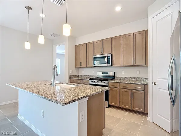a kitchen with stainless steel appliances granite countertop a sink a stove a refrigerator a center island with wooden floor and cabinets