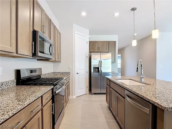 a kitchen with stainless steel appliances granite countertop a sink a stove and a wooden cabinets