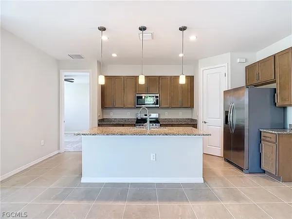 a large kitchen with granite countertop a large counter top stainless steel appliances and cabinets