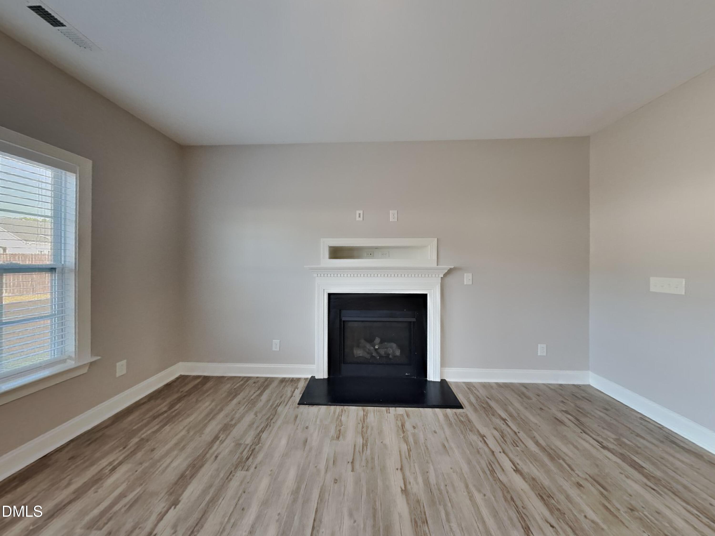 93 Jonalker Court Clayton, NC 27520 - Photo 2 of 17 an empty room with wooden floor fireplace and windows