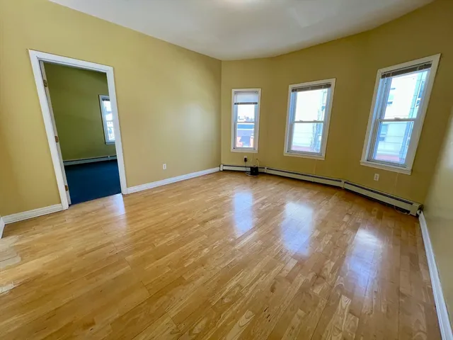 a view of an empty room with window and wooden floor