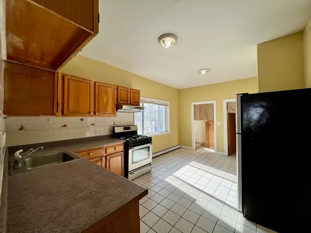 a kitchen with stainless steel appliances granite countertop a refrigerator a stove and a sink