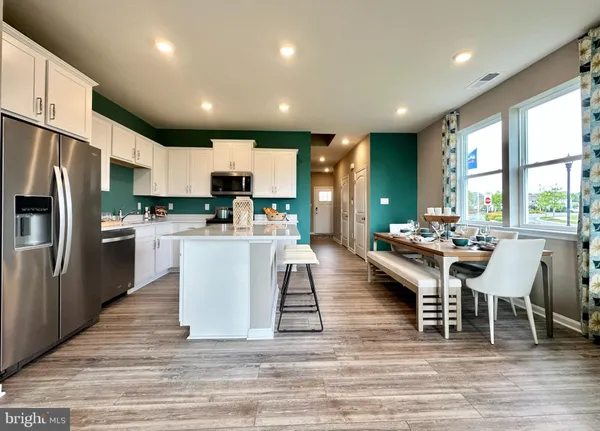 a large kitchen with stainless steel appliances kitchen island granite countertop a large kitchen island a stove a refrigerator a sink dishwasher a dining table and chairs with wooden floor