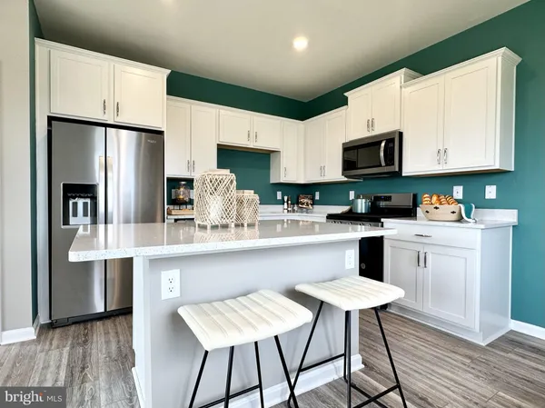 a kitchen with stainless steel appliances a microwave a stove a refrigerator a sink a stove with white cabinets and wooden floor