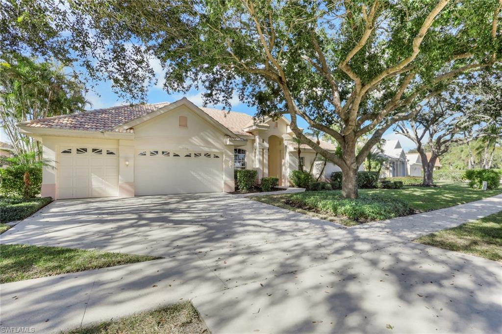 View of front of property with stucco siding, a garage, driveway, a tile roof, and a front lawn