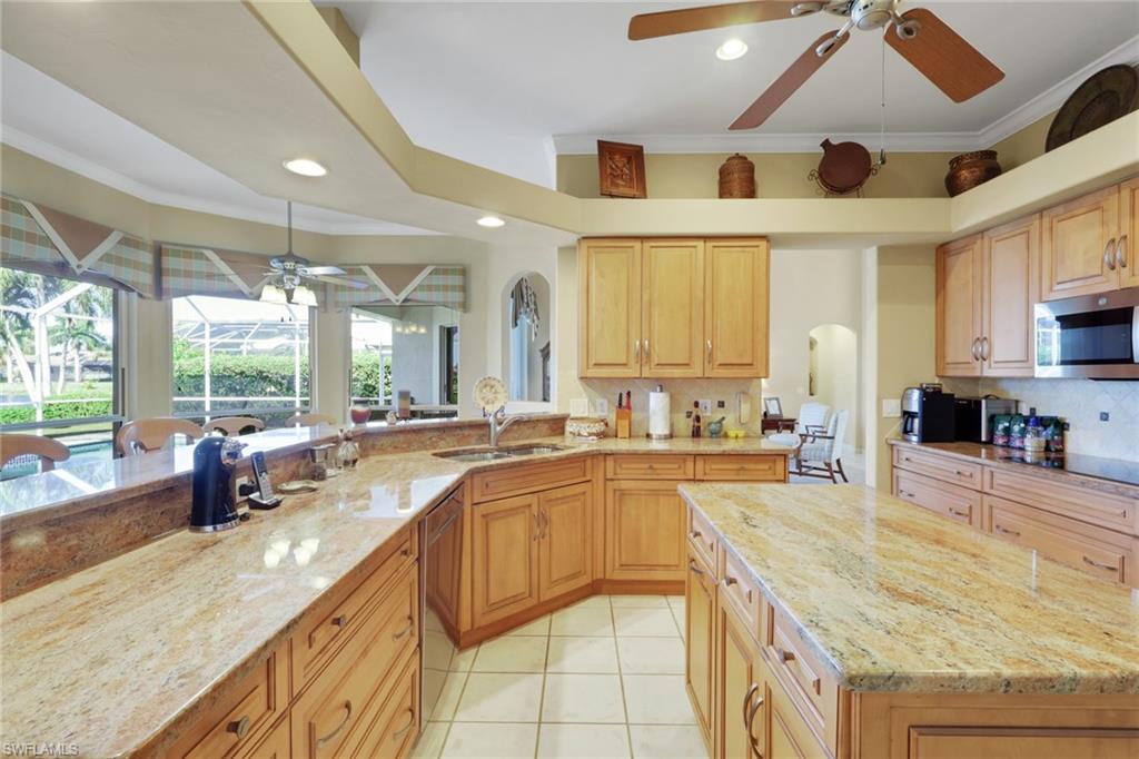 11079 Phoenix Way Naples, FL 34119 - Photo 2 of 30 Kitchen featuring a ceiling fan, crown molding, light stone counters, stainless steel appliances, and a center island