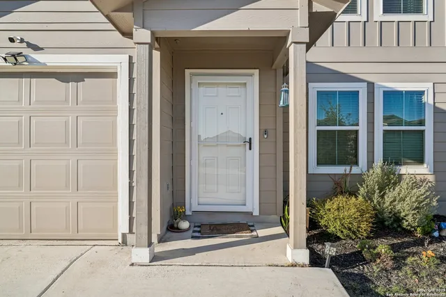 a front view of a house with a potted plants and wooden fence
