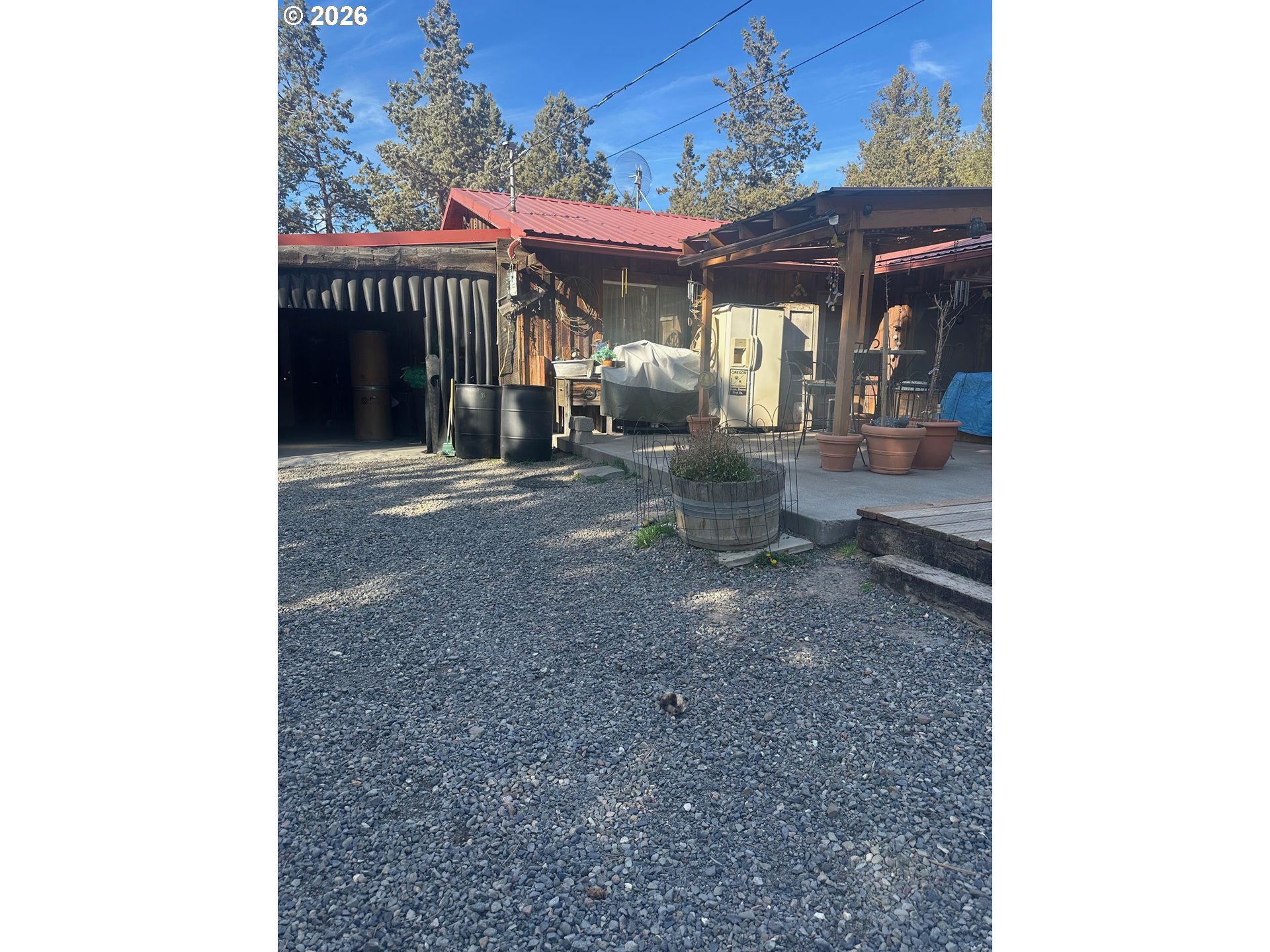 6792 Southeast Juniper Canyon Road Prineville, OR 97754 - Photo 16 of 44 a view of a patio with table and chairs under an umbrella with large trees