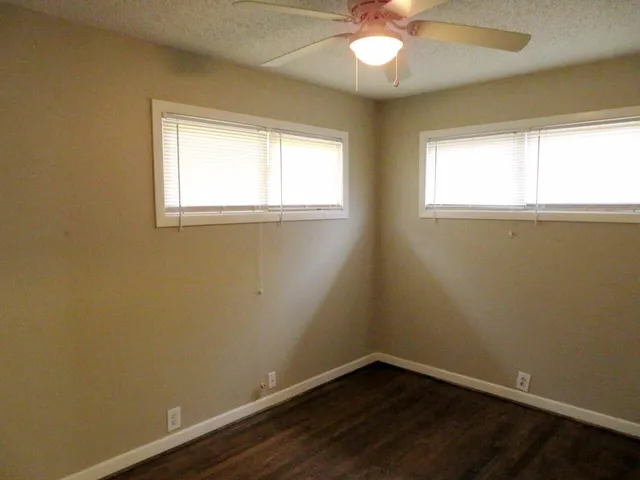 an empty room with a window and a fan