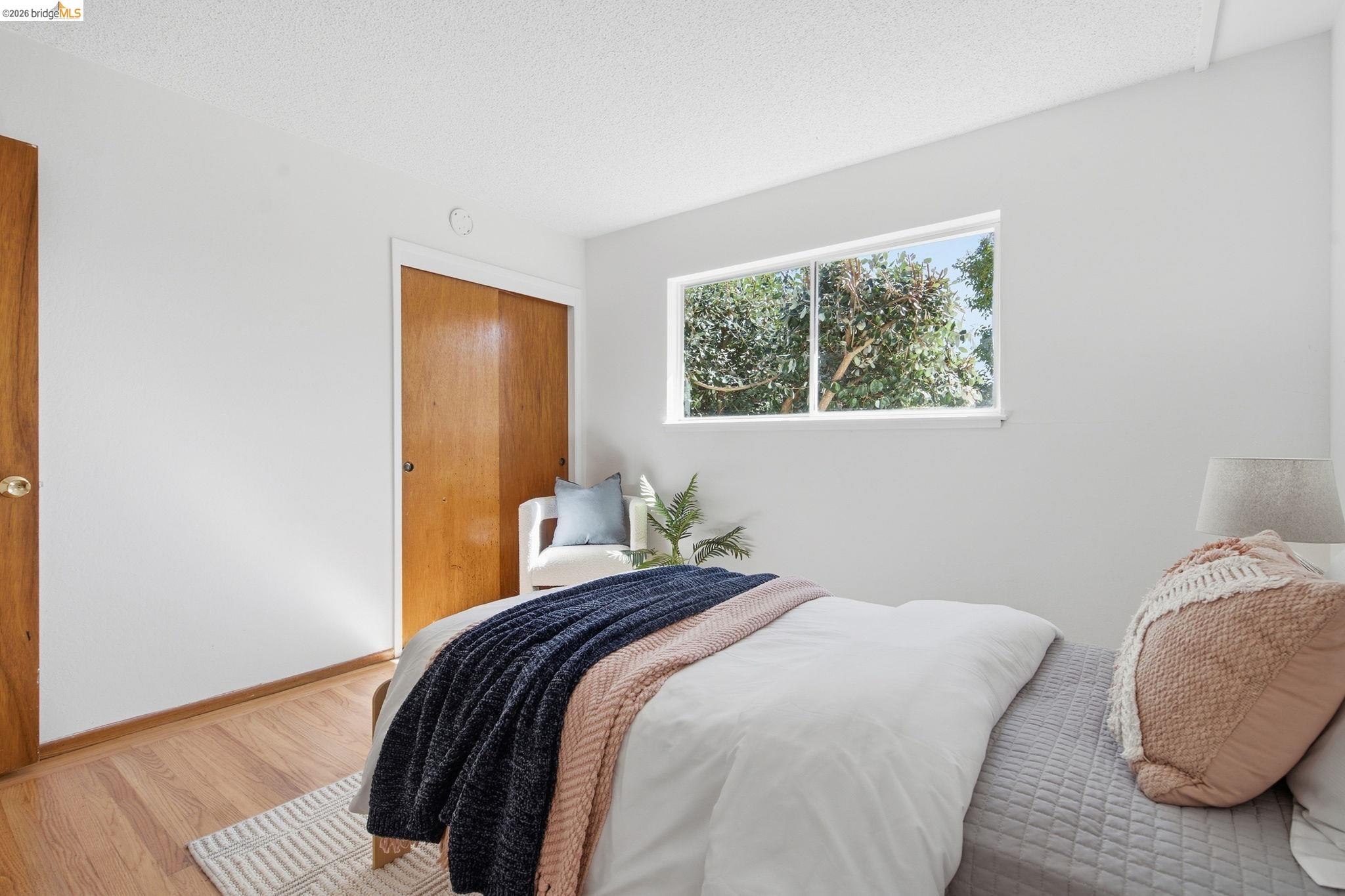4522 Santa Rita Road El Sobrante, CA 94803 - Photo 19 of 58 Hardwood-style flooring with bright white walls, a large window, and a wood-paneled sliding closet door