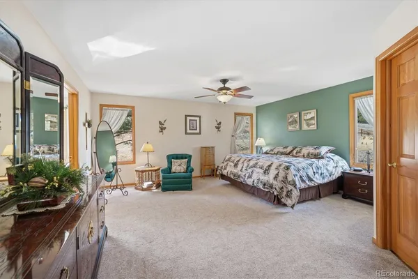 a bedroom with a bed couch chandelier and a window