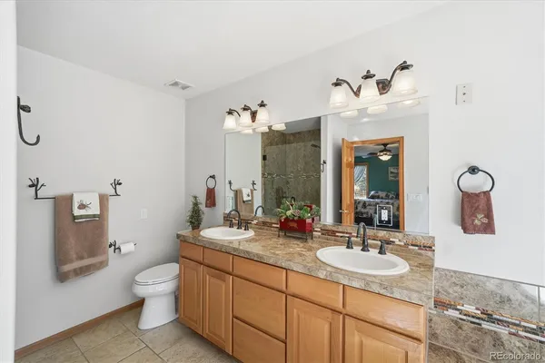 a bathroom with a granite countertop sink a toilet and mirror