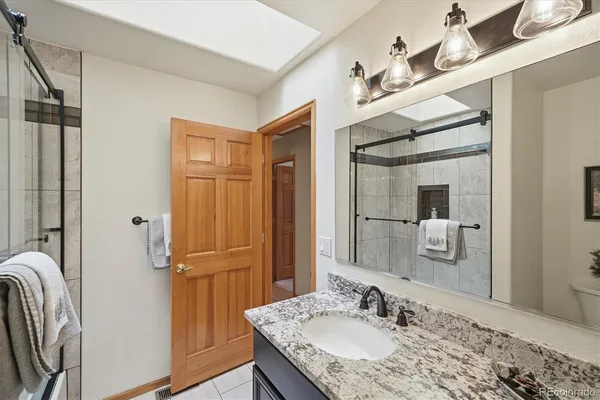 a bathroom with a granite countertop sink a mirror and a shower