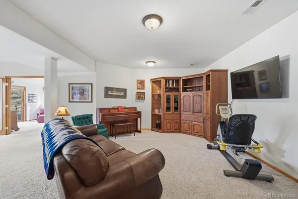 a living room with furniture a flat screen tv and gym equipment