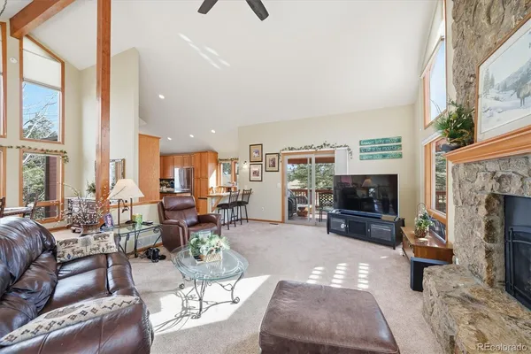 a living room with furniture a fireplace a flat screen tv and large windows
