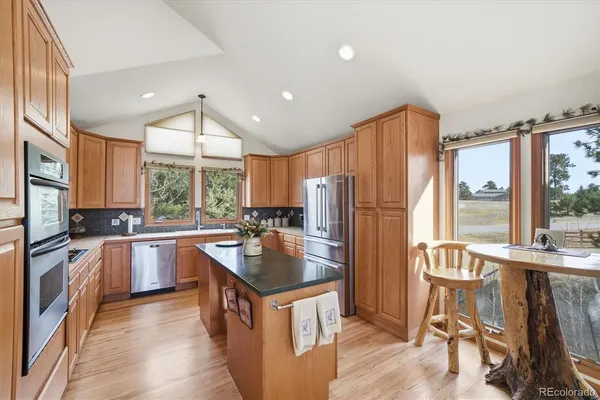 a kitchen with stainless steel appliances granite countertop a refrigerator a sink a stove and a refrigerator