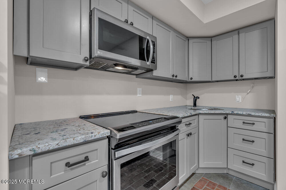 609 Higgins Avenue, Unit 3 Brielle, NJ 08730 - Photo 10 of 25 a kitchen with granite countertop a stove sink and microwave